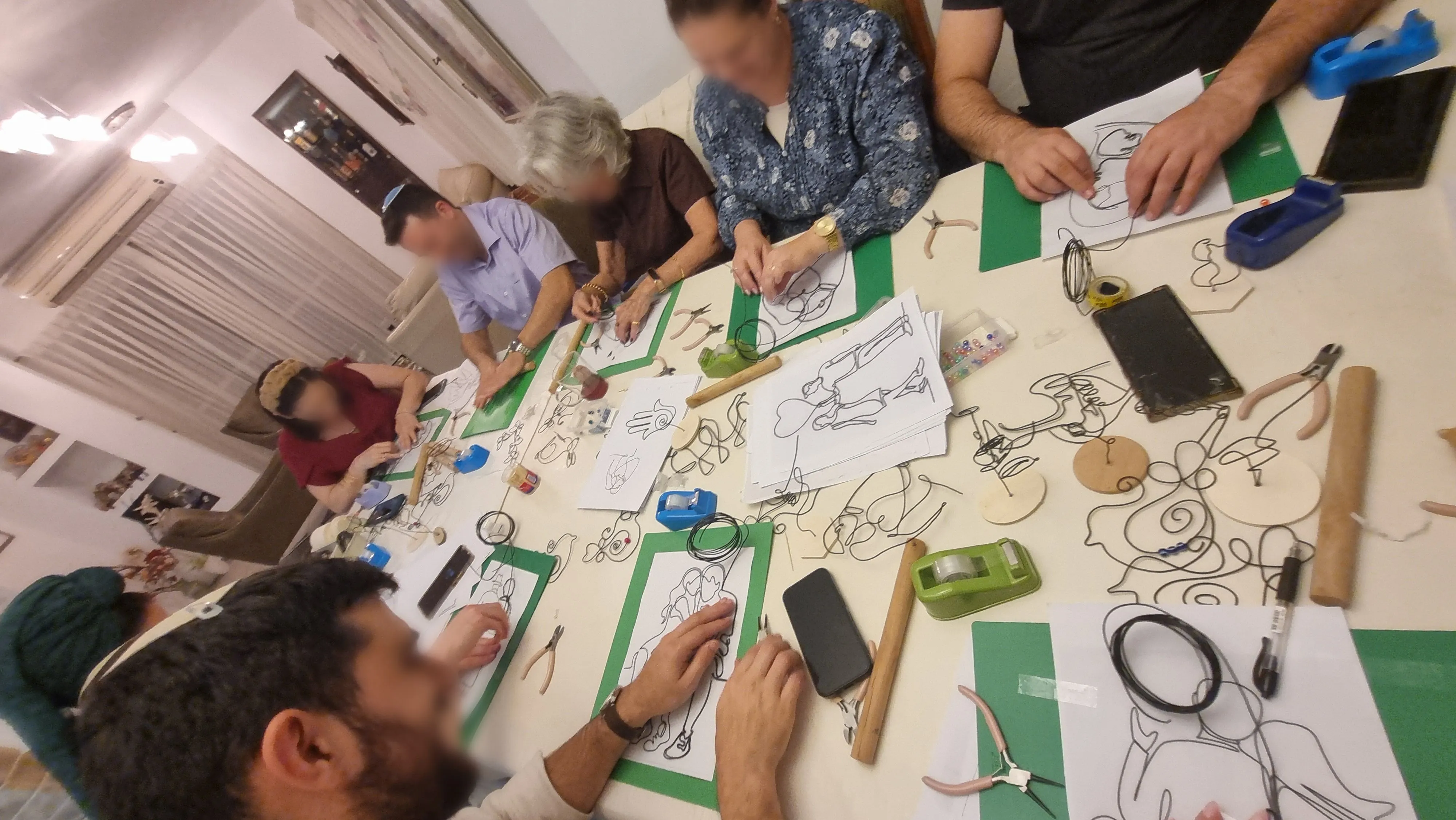 משתתפים בסדנא קבוצתית שישובים ומכופפים ברזל ,בשולחן גדול